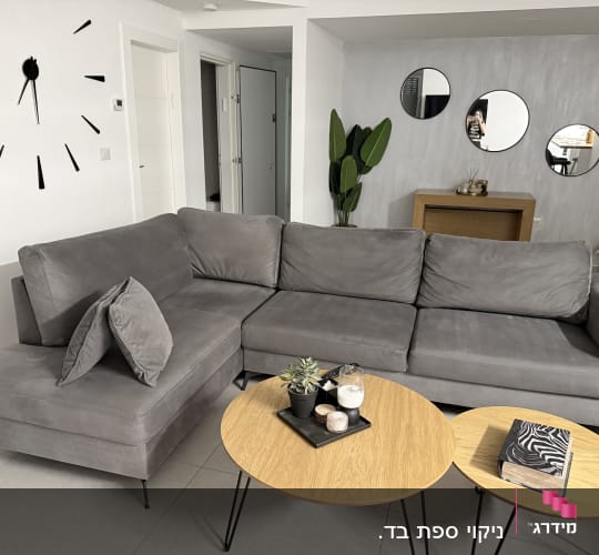 ספה אפורה בחדר מגורים עם שולחנות עץ קטנים